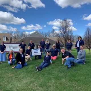A group of people posing for a photo on a grassy area under a cloudy sky.