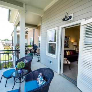 A cozy balcony with stylish outdoor seating and modern decor, offering a relaxing spot in an apartment setting.