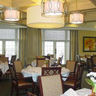 A well-lit dining room with neatly arranged tables and chairs, featuring elegant decor.