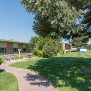 A serene outdoor area with a lawn, pathway, and trees in front of a building.