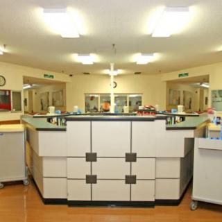 A hospital nurse station with a central reception desk and medical equipment.