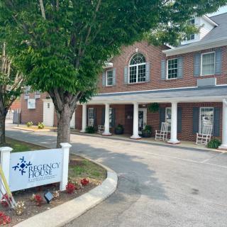 The exterior of a brick building with a sign and trees in the foreground.