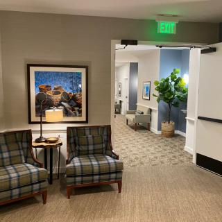 A cozy hallway with upholstered chairs, artwork on the wall, and decorative plants.