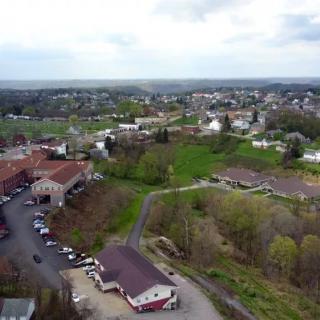Aerial view of a small town surrounded by greenery and an overcast sky.