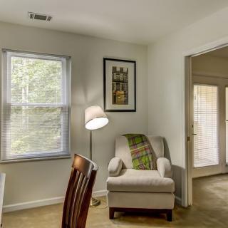 A cozy living room corner with a comfortable armchair, floor lamp, and window view.