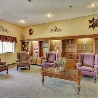 A cozy living room featuring armchairs, a wooden coffee table, and decorative cabinets.