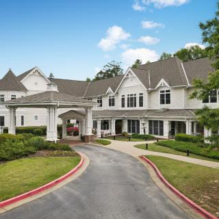 A large, elegant building with a welcoming driveway and landscaped surroundings.
