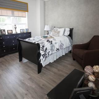 A modern bedroom with a single bed, dresser, and chair.