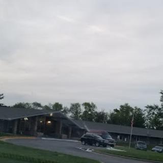 A cloudy day over a building with vehicles parked outside.