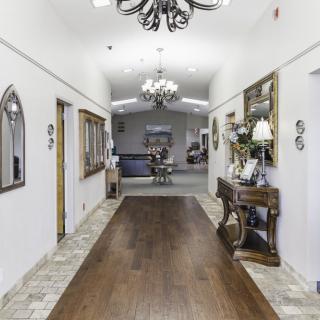 A beautifully decorated hallway with chandeliers, wooden floors, and mirrors.