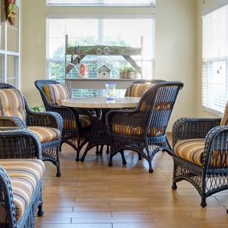 A cozy dining area with wicker chairs and a round table set against large windows allowing natural light in.