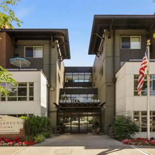 A modern building entrance with an American flag and well-maintained landscaping.