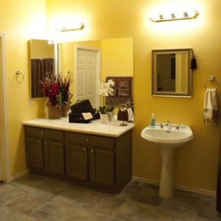 A cozy bathroom featuring yellow walls, a vanity with decorative flowers, and a modern sink.