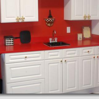 A modern kitchen featuring a striking red countertop and white cabinets.
