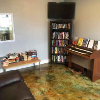 A cozy living room with a bookshelf, piano, and television.