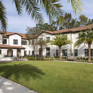 A large house with palm trees and a well-maintained garden.