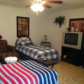 A cozy bedroom featuring two twin beds, a ceiling fan, and an old-style television.