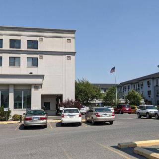 A hotel building with a parking lot full of cars during the daytime.