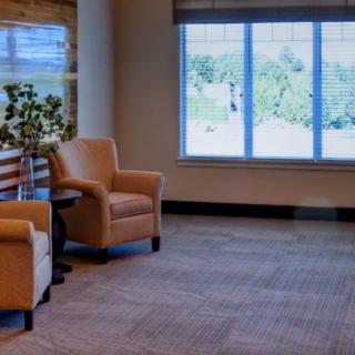 A cozy living room with comfortable chairs near large windows letting in natural light.