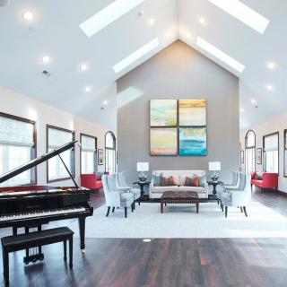 A modern living room with a grand piano, vaulted ceiling, and contemporary artwork.