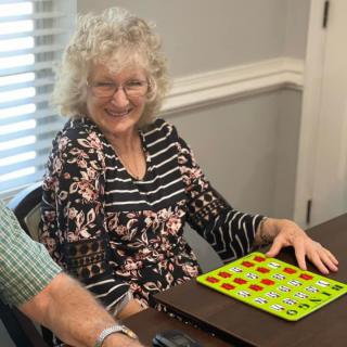 A smiling woman playing bingo indoors.
