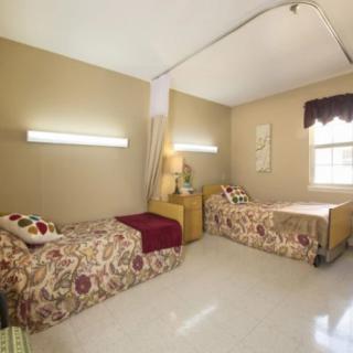 A simple bedroom with twin beds and warm lighting.