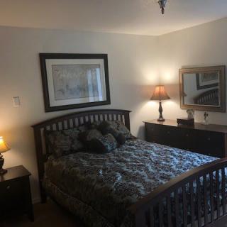 A cozy bedroom with a bed, bedside tables, lamps, and decorative wall art.