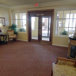 A cozy lobby area with seating, carpet flooring, and a glass entrance door.