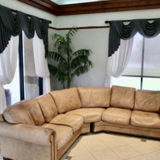 A cozy living room featuring a large sectional sofa with elegant curtains and a potted plant by the window.