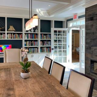 A well-designed dining room with bookshelves, a large wooden table, and elegant lighting.