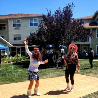Two people dancing outdoors in costumes during a sunny day.