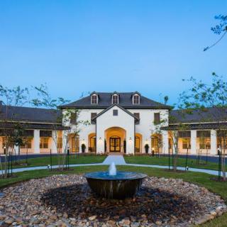 A large, elegant building with a central fountain and landscaped surroundings during the evening.