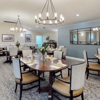 An elegant dining room featuring stylish chandeliers, neatly arranged tables, and comfortable chairs.