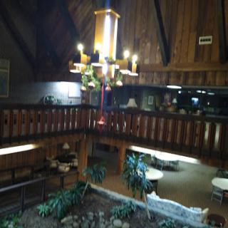 A cozy lodge interior featuring a wooden design, a decorative chandelier, and ample seating arrangements.