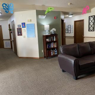 A cozy office waiting area with a sofa and a bookshelf.