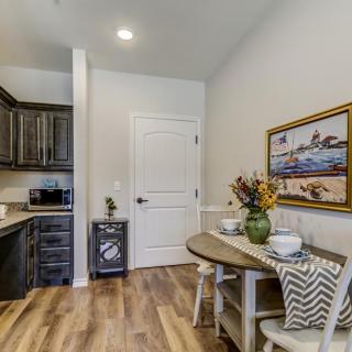 A modern kitchen and dining area with a small round table set against a wooden floor, featuring elegant decor and artwork.