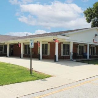 A school building with a parking area and a partly cloudy sky.