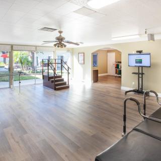 Spacious gym with wood flooring and bright lighting, featuring exercise equipment.
