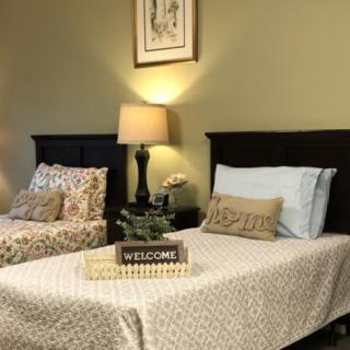 A cozy bedroom with two neatly made beds, a lamp on a side table, and a welcome sign adding a touch of hospitality.