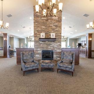 A cozy lounge area featuring two chairs and a stone fireplace, illuminated by elegant chandeliers.