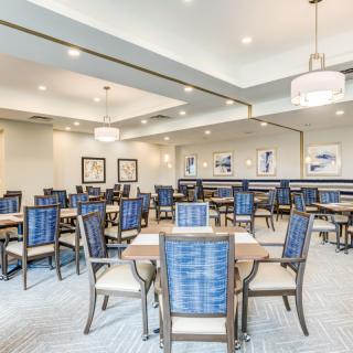 A modern dining room with neatly arranged tables and chairs under bright ceiling lights.