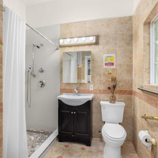 A compact and modern bathroom featuring a shower, toilet, and sink with elegant tile work.