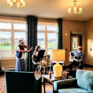 A group of musicians performing in a cozy living room setting.