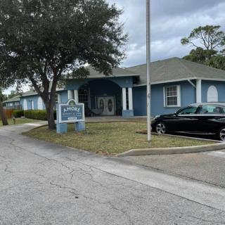 A blue building with a car parked in front, situated on a cloudy day.
