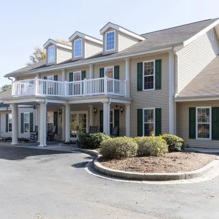 A two-story residential building with a porch and multiple windows.