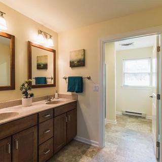 A modern bathroom with double sinks and wooden cabinets.
