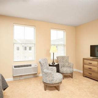 A cozy living room with two chairs, a lamp, and a television.