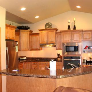 A modern kitchen featuring wooden cabinetry and a spacious granite countertop.
