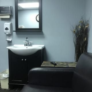 A cozy waiting room featuring a sink, mirror, and comfortable seating.