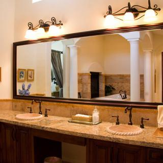 A stylish bathroom featuring a large mirror, double sink vanity, and elegant lighting.